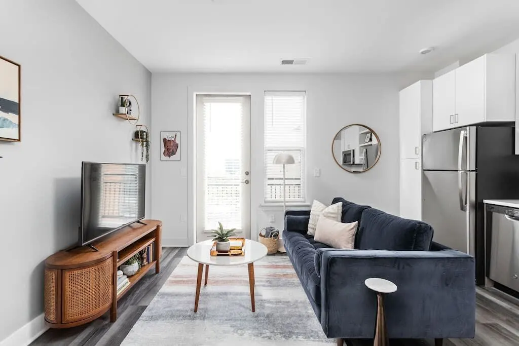 Open plan living room and kitchen with a navy sofa and bar stools in a Roadmap Lodging home in Indianapolis